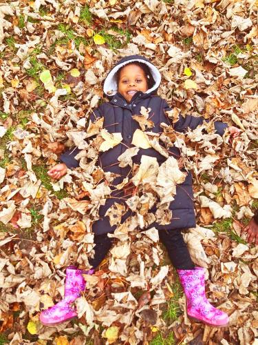 Garden_child_laying_in_leaves